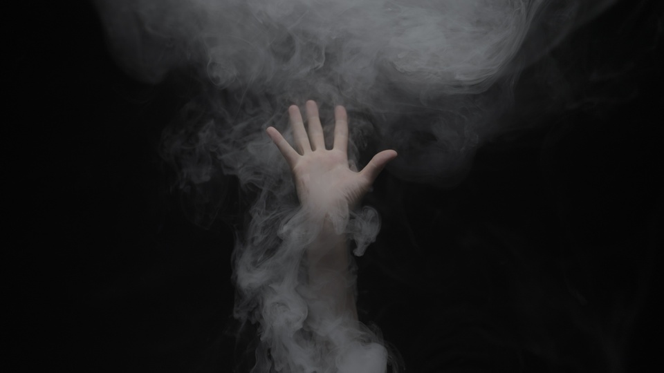 Mano che si allunga verso l’alto attraverso la nebbia