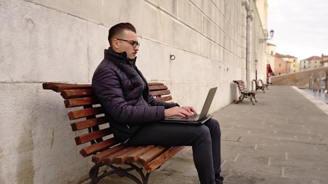 Focused Man Working Remotely on Laptop by Canal