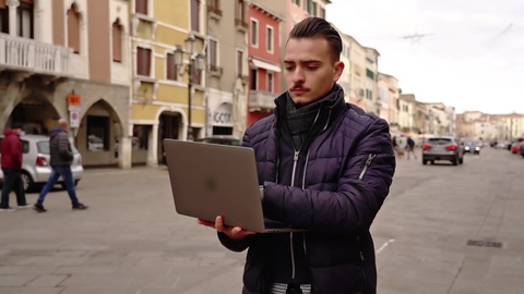 Uomo che Scrive al Laptop Mentre Sta in Piedi in una Strada Cittadina