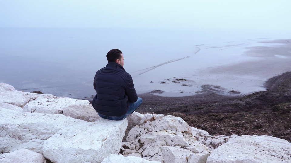 Uomo riflessivo sulla riva tranquilla