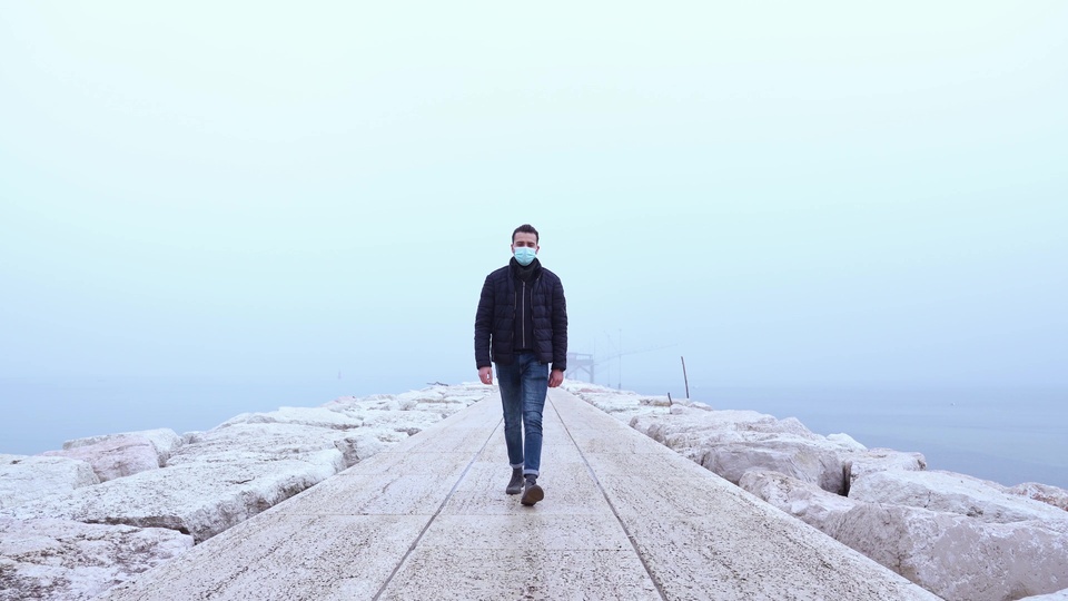 Man Walking on a Foggy Pier with Face Mask